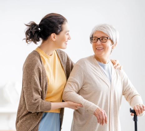 A female assisting a senior woman to stand