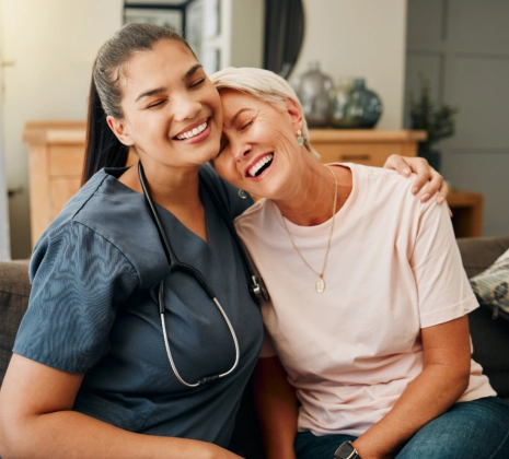 A female caregiver and a senior woman hugging each other