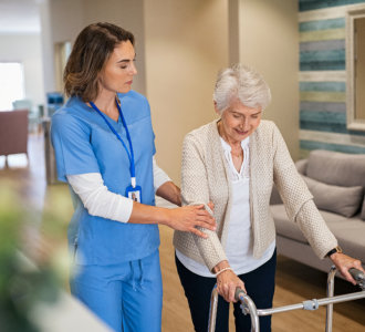 aide assisting the senior woman to walk