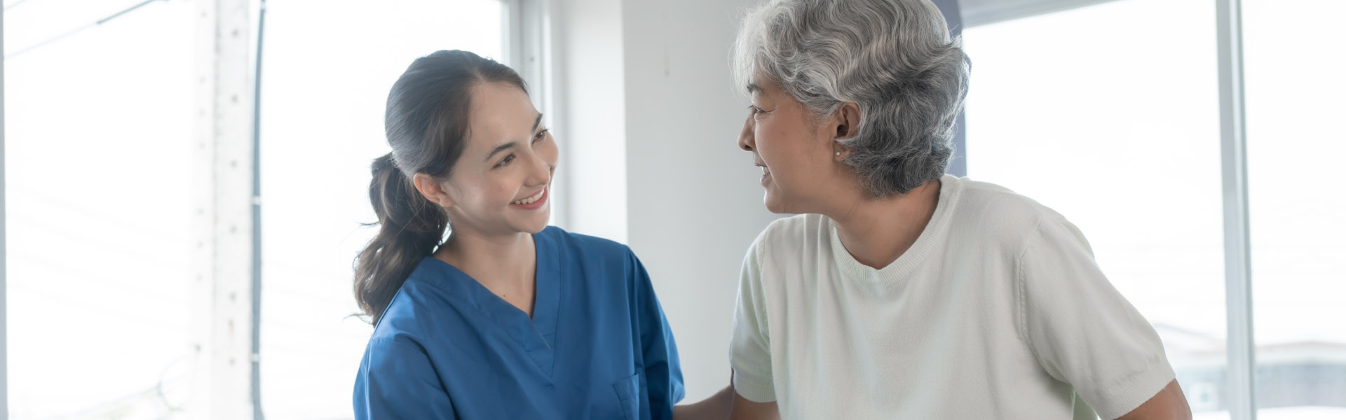 aide and senior woman smiling at each other